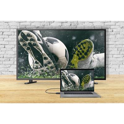 Telewizor i laptop wyświetlają ten sam obraz: buty piłkarskie w akcji, kopiące mokrą piłkę.