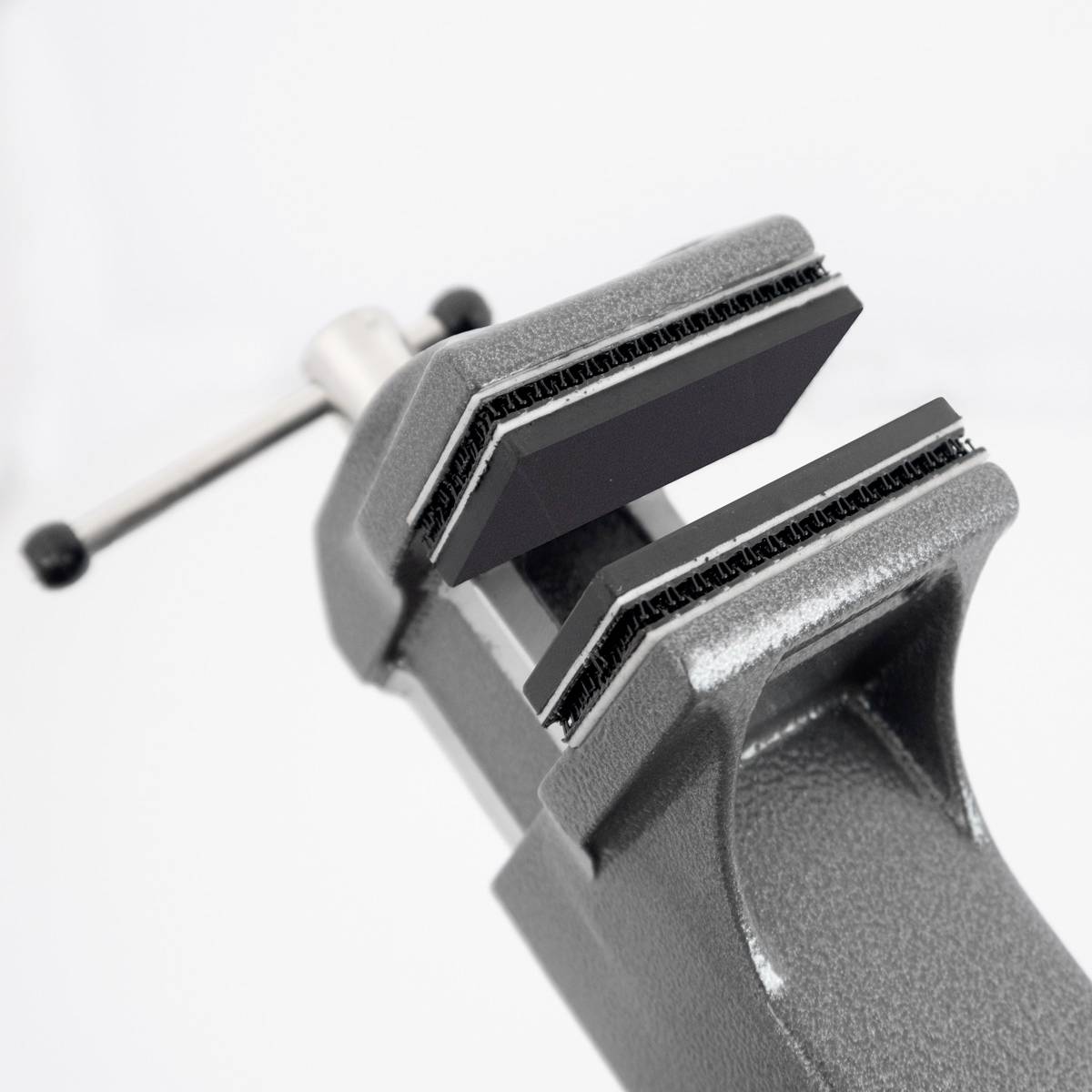 Szara ścisk śrubowa jest otwarta i gotowa do zamocowania przedmiotów. Zaciski są wyłożone materiałem ochronnym, aby zapobiec uszkodzeniom.