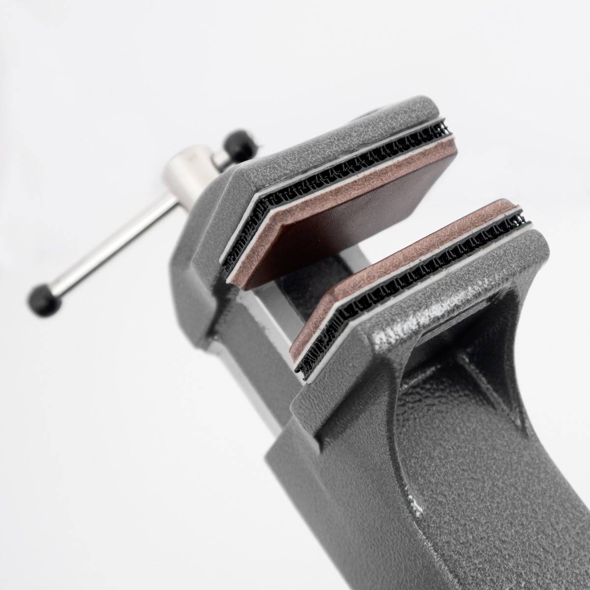 Imadło z dużymi, otwartymi szczękami, trzymane przez srebrną śrubę na jasnoszarym tle.