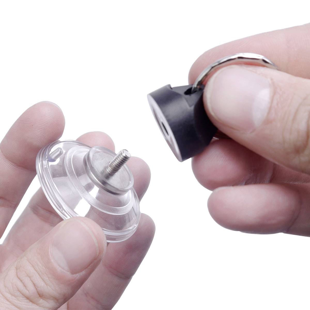 Jedna ręka trzyma przezroczystą uchwyt z przyssawką i śrubą, podczas gdy druga ręka mocuje nad nią czarną nasadkę.