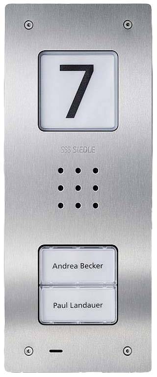 Srebrny panel domofonowy z dwoma tabliczkami z nazwiskami: 'Andrea Becker' i 'Paul Landauer'. Na górze widnieje cyfra '7'.