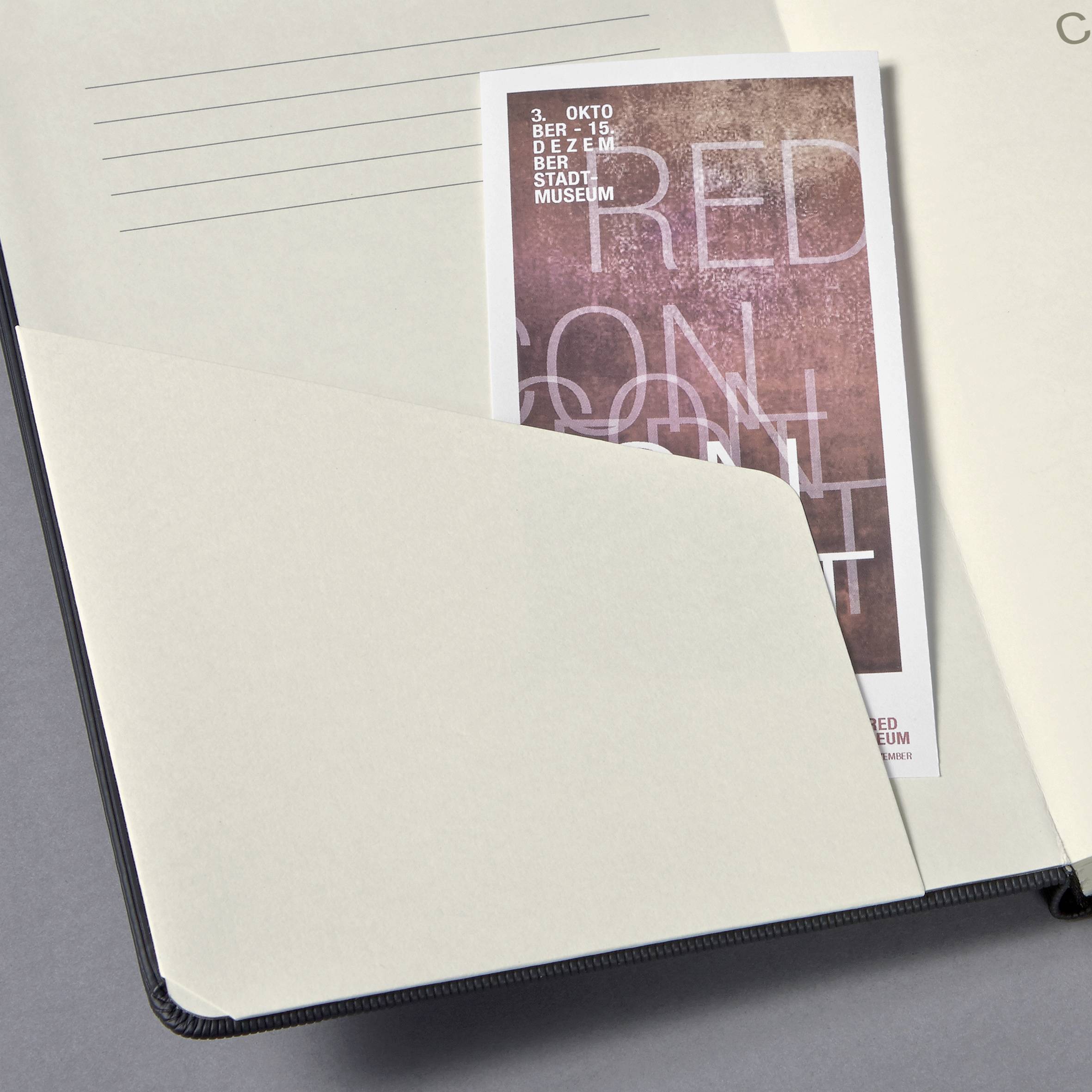 Notatnik z częściowo zasłoniętą ulotką wydarzenia w muzeum miejskim, zaplanowanego na 3 października.
