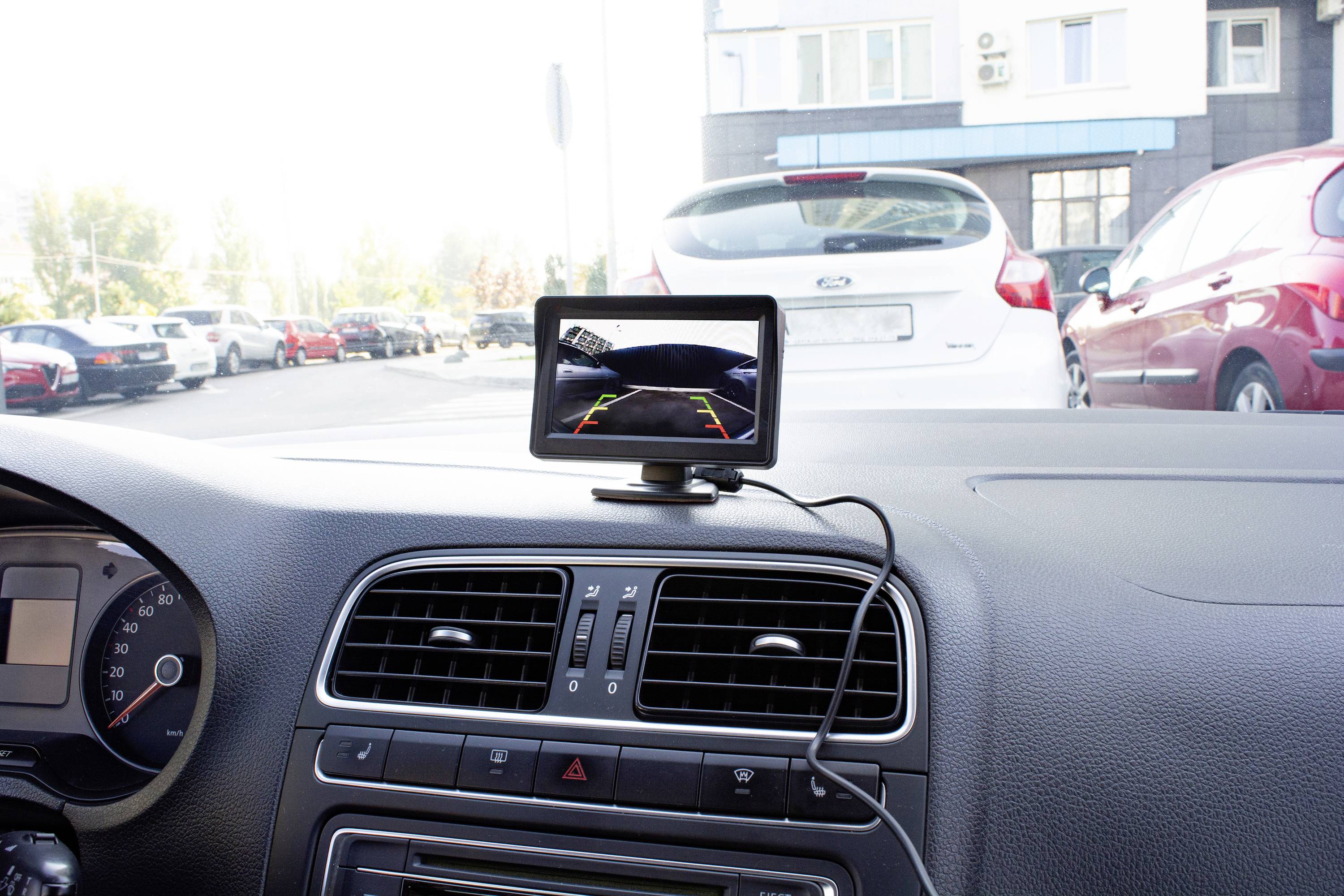 Wnętrze samochodu z wbudowanym monitorem kamery cofania, który wyświetla obraz otoczenia za samochodem na ekranie.