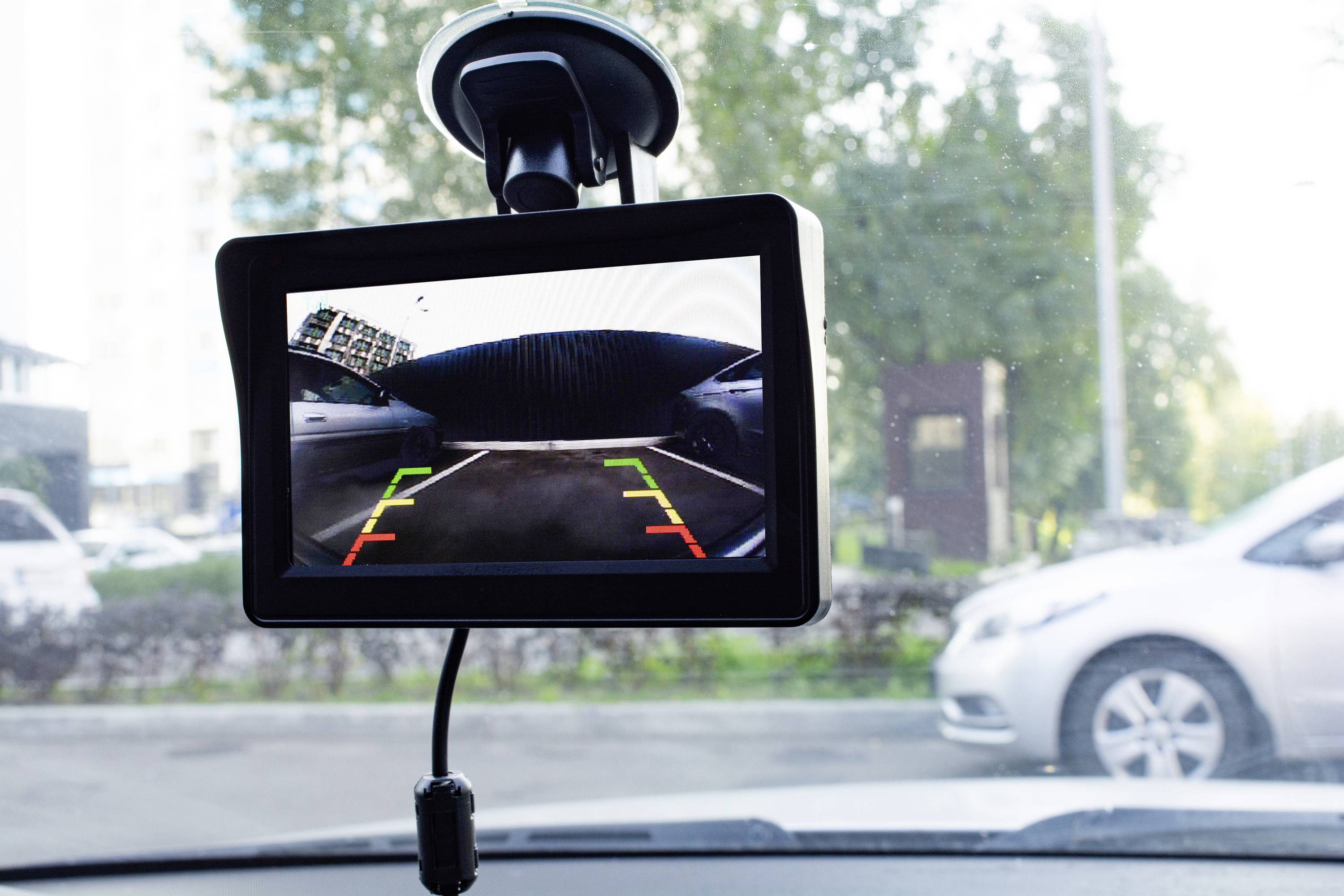 Wyświetlacz samochodu pokazuje obraz kamery cofania z kolorowymi liniami wizualizującymi odległość od przeszkody.