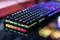 Klawiatura dla graczy z kolorowymi klawiszami RGB na ciemnym stole. Kolory świecą żywo i odzwierciedlają atmosferę gamingu.