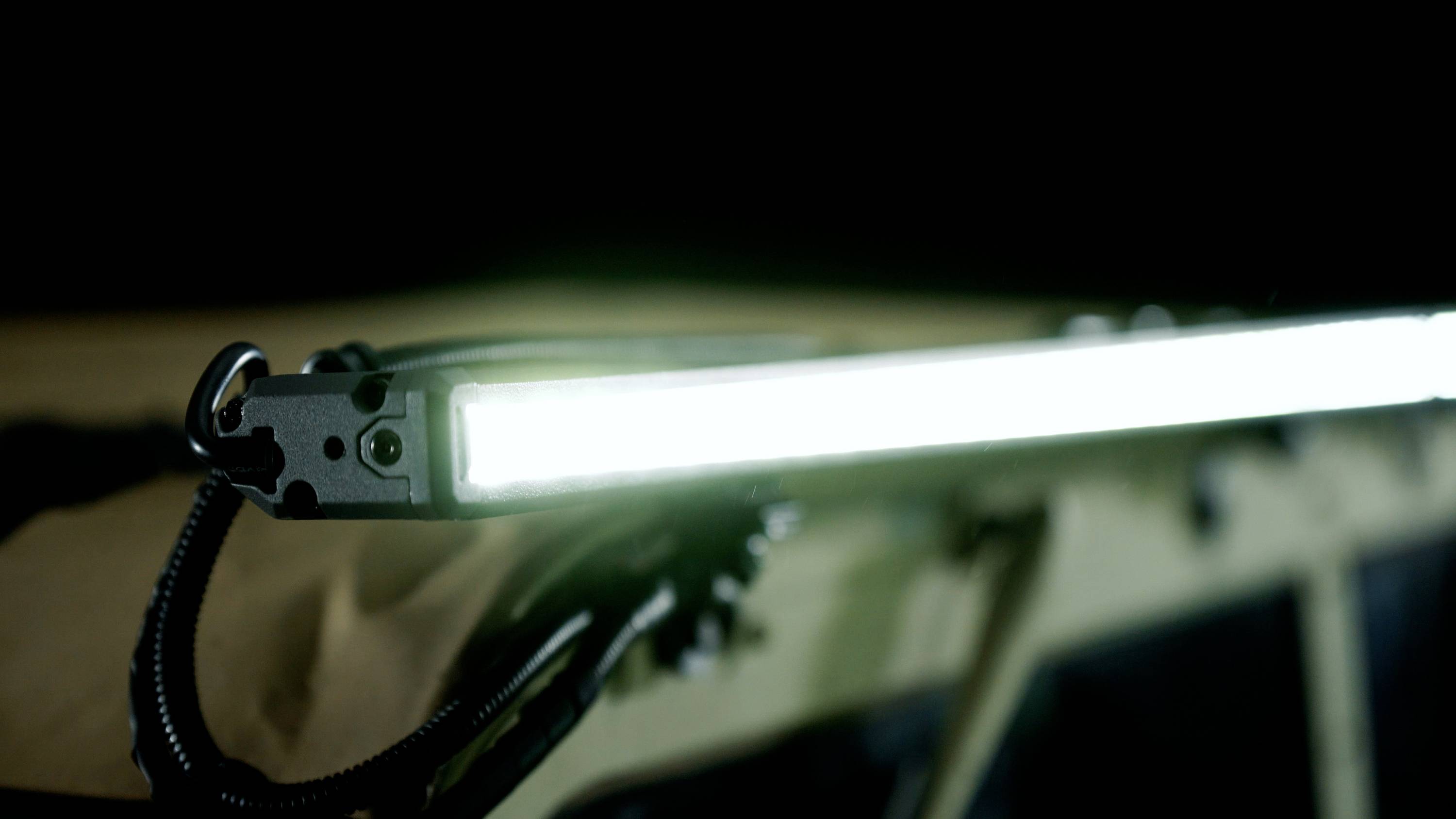 Świecąca listwa LED zamontowana na ciemnym tle. Wydaje się być rozwiązaniem oświetleniowym we wnętrzu dachu pojazdu.