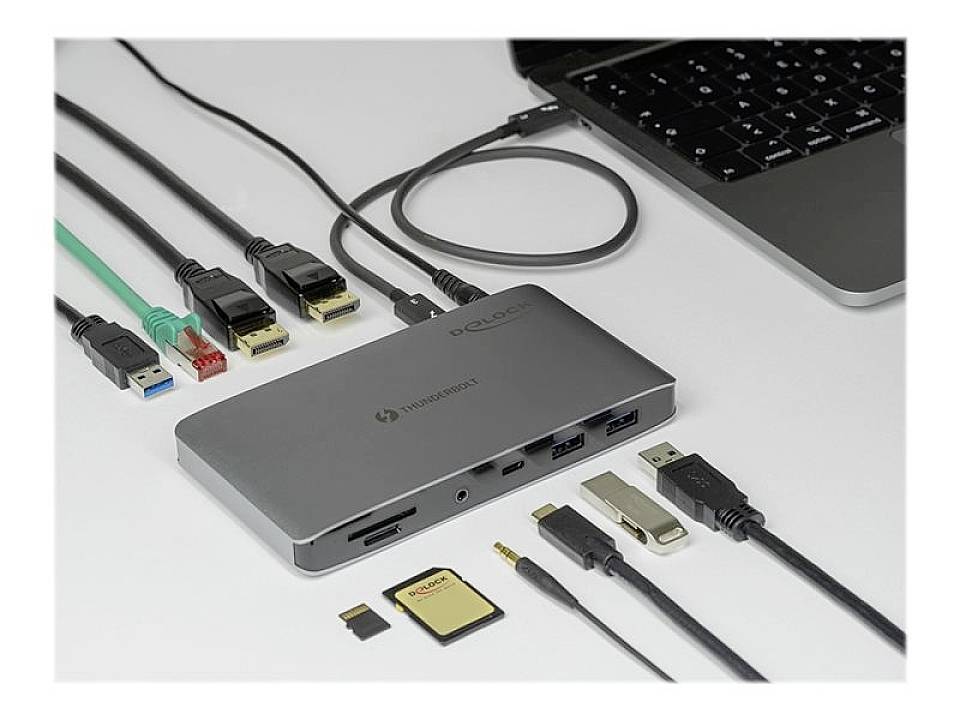 Concentrator USB-C z wieloma portami jest podłączony do laptopa. Widać różne kable, karty i typy złączy.