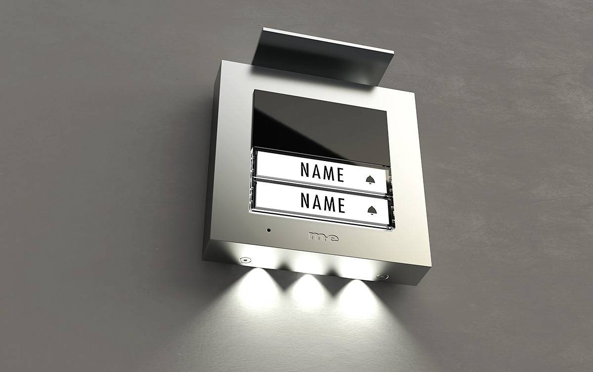 Tabliczki z nazwiskami przy nowoczesnym panelu domofonowym, z podświetlanymi przyciskami.