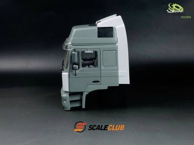 Model szarej kabiny ciężarówki na czarnym tle, na podłodze logo 'SCALECLUB', dodatkowe logo w górnym lewym rogu.