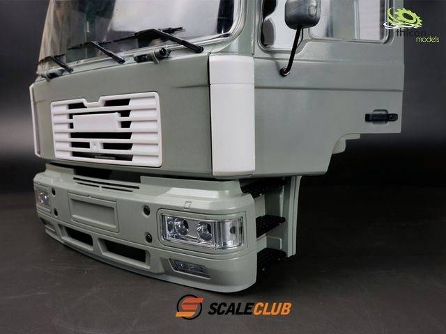 Przednia część modelu ciężarówki w jasnoszarym kolorze z dokładnie odwzorowanym zderzakiem i reflektorami, na czarnym tle. Widoczne logo marki 'Scale Club'.