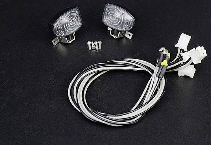 Dwie lampy samochodowe z zamontowanymi kablami i śrubami na czarnym tle.