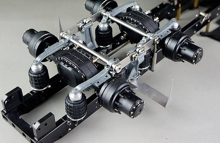 Zbliżenie mechanizmu jezdnego z wieloma kołami i złożonymi systemami zawieszenia, prawdopodobnie z modelu pojazdu.