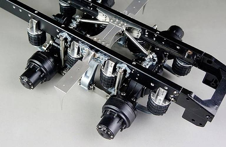 Zbliżenie podwozia z wieloma osiami i poprzeczkami. Wyraźnie widoczne są komponenty zawieszenia oraz punkty mocowania.