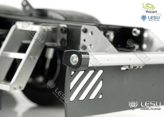 Zbliżenie podwozia modelu ciężarówki z metalowymi elementami i oświetleniem LED. Widoczne są logotypy marek 'thicon' i 'LESU'.