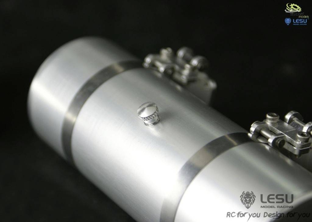 Srebrny cylinder z wąskimi metalowymi paskami i śrubą na czarnym tle. W prawym górnym rogu dwa nieczytelne logo, na dole nazwa marki.