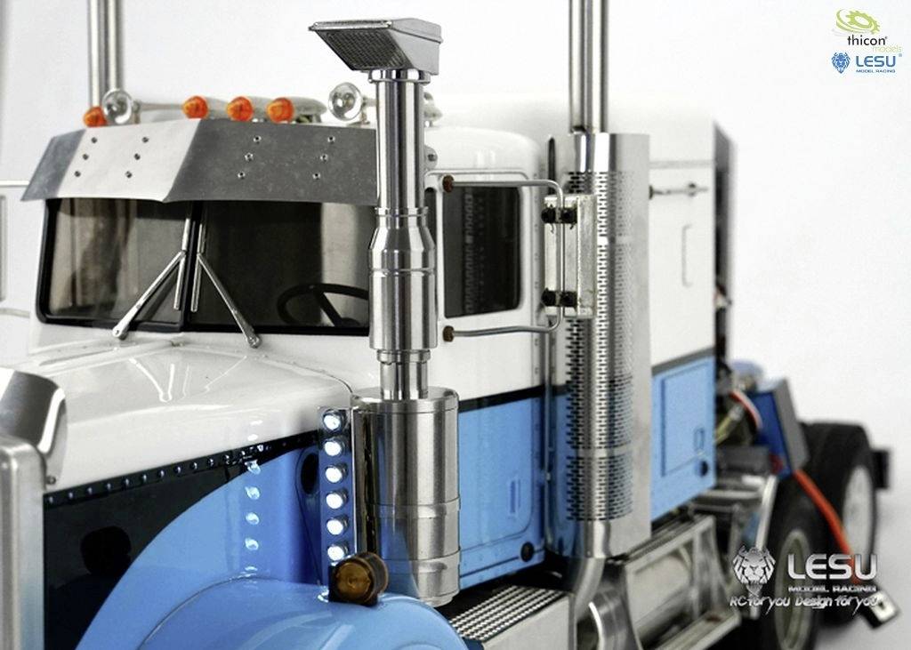 Zbliżenie modelu ciężarówki w kolorach niebieskim i białym z chromowanymi detalami. Po lewej stronie widoczne są logo i dane kontaktowe firm.