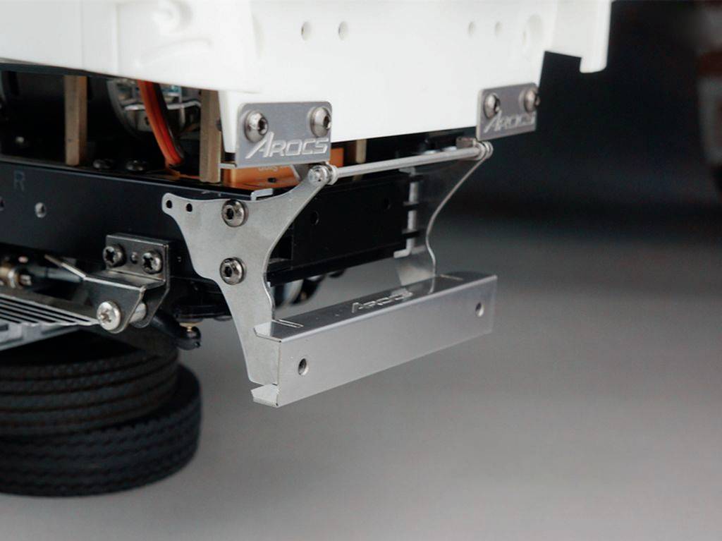 Zbliżenie metalowej części urządzenia mechanicznego z śrubami i mocowaniami, zamontowanej na czarnej ramie.