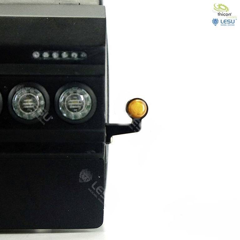 Czarna część pojazdu z dwoma okrągłymi reflektorami i małym pomarańczowym światłem z boku, na białym tle.