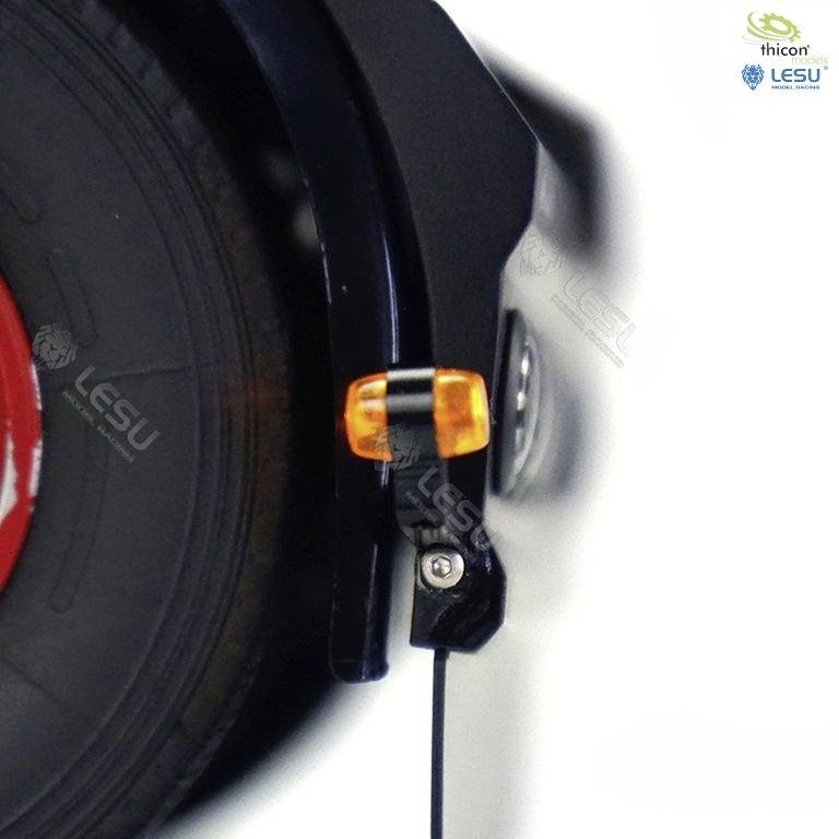 Zbliżenie czarnego błotnika rowerowego z małym pomarańczowym odblaskiem i oponą w tle.