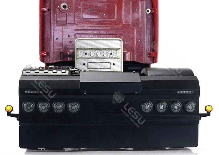 Czerwona rama samochodu ciężarowego z otwartą, unoszoną kabiną kierowcy, z widocznym poniżej obszarem silnika, wraz z reflektorami i kierunkowskazami.