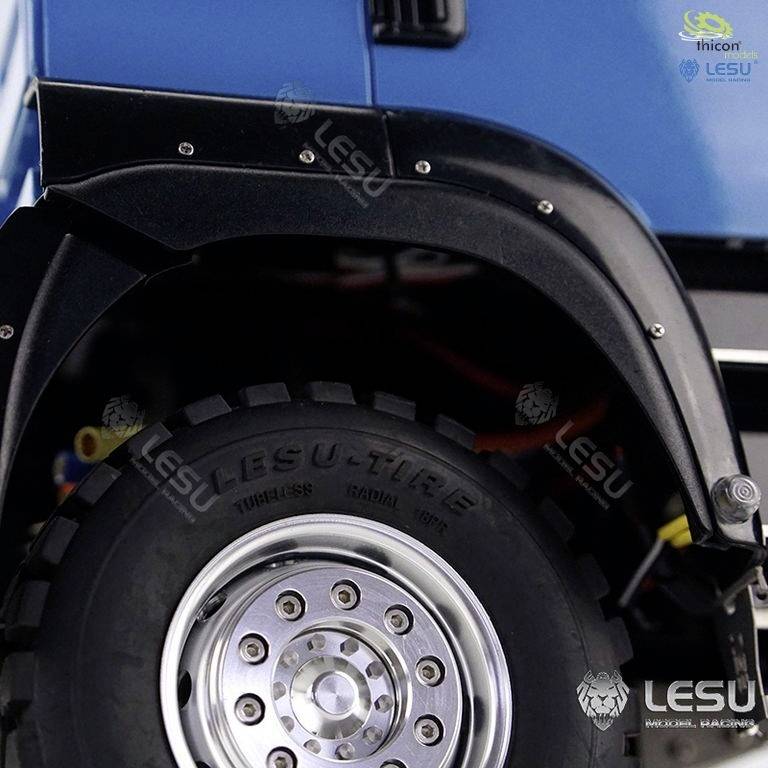 Zbliżenie czarnej błotnicy i opony niebieskiego pojazdu z wydrukowanym logo 'LESU'.