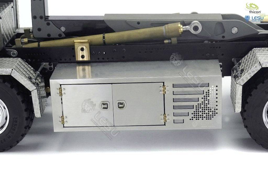 Model ciężarówki z dokładnie wykonaną metalową ramą i skrzynką ładunkową z boku, prezentowany na płaskiej, białej powierzchni.