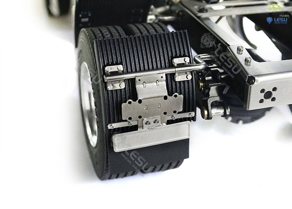 Zbliżenie tylnego koła ciężarówki z dokładnie widocznym zawieszeniem i mocowaniem. Metalowe struktury podkreślają techniczną precyzję.