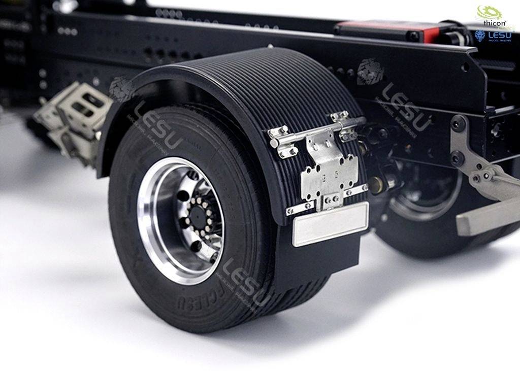 Zbliżenie tylnego koła ciężarówki z błyszczącą felgą i szczegółowo widocznym systemem zawieszenia. W tle widoczne są części podwozia.