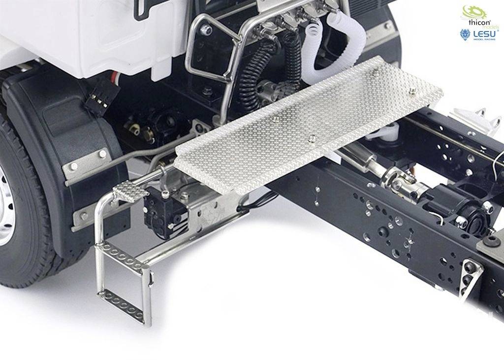 Modelowy samochód ciężarowy z otwartą komorą silnika, ukazujący szczegółowe elementy podwozia. Z przodu zamontowana jest metalowa platforma.