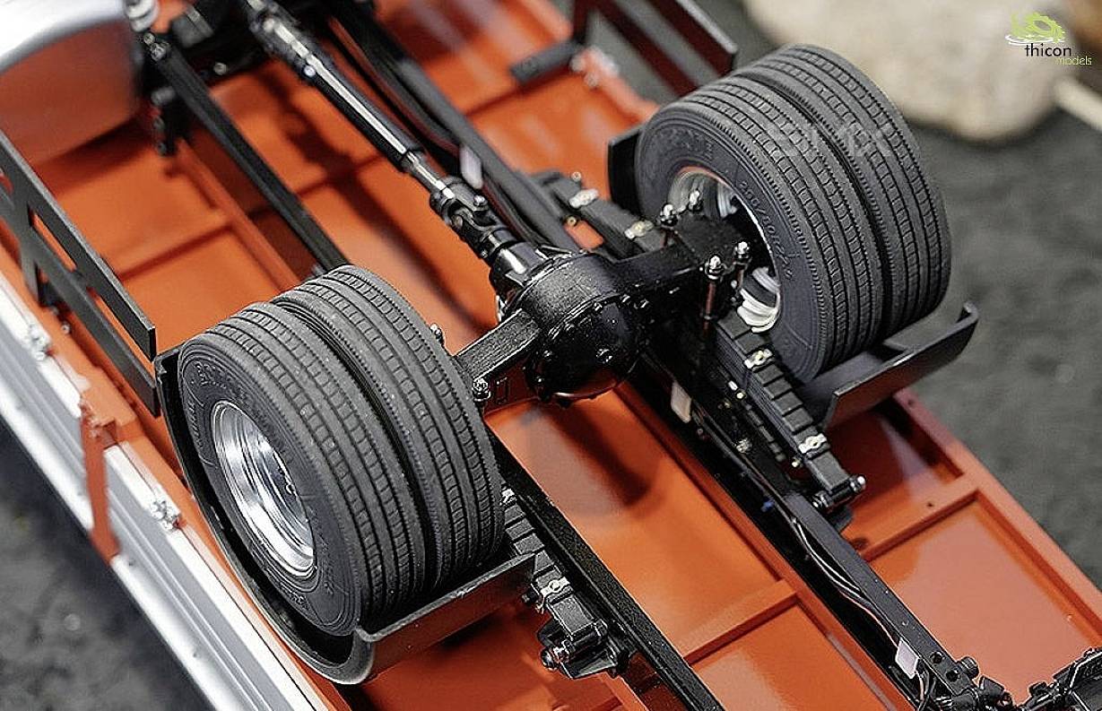 Widok spodu pojazdu z dokładnym wejrzeniem w układ jezdny i konstrukcję osi, w tym opony i podwozie.