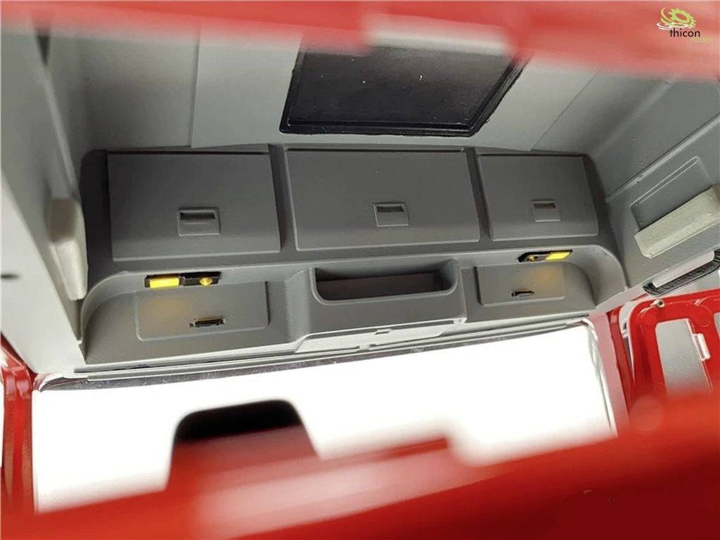 Widok wnętrza kabiny modelu pojazdu z szarymi schowkami i przegródkami. Widoczne są czerwone krawędzie zewnętrzne modelu.