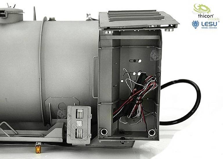 Szare urządzenie mechaniczne z otwartą przegródką, w której widocznych jest kilka przewodów. W prawym górnym rogu znajdują się dwa logotypy.