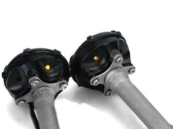 Dwa mechaniczne elementy konstrukcyjne z czarnymi osłonami i metalowymi rurami; świecące punkty w ich centrach, na białym tle.