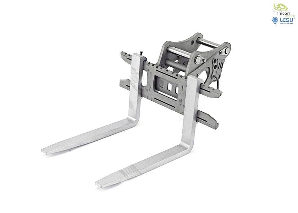 Widelec wózka widłowego wykonany z metalowego stopu w kolorze srebrnym, z dwoma pionowo skierowanymi do przodu zębami. W prawym górnym rogu widoczne dwa logotypy.