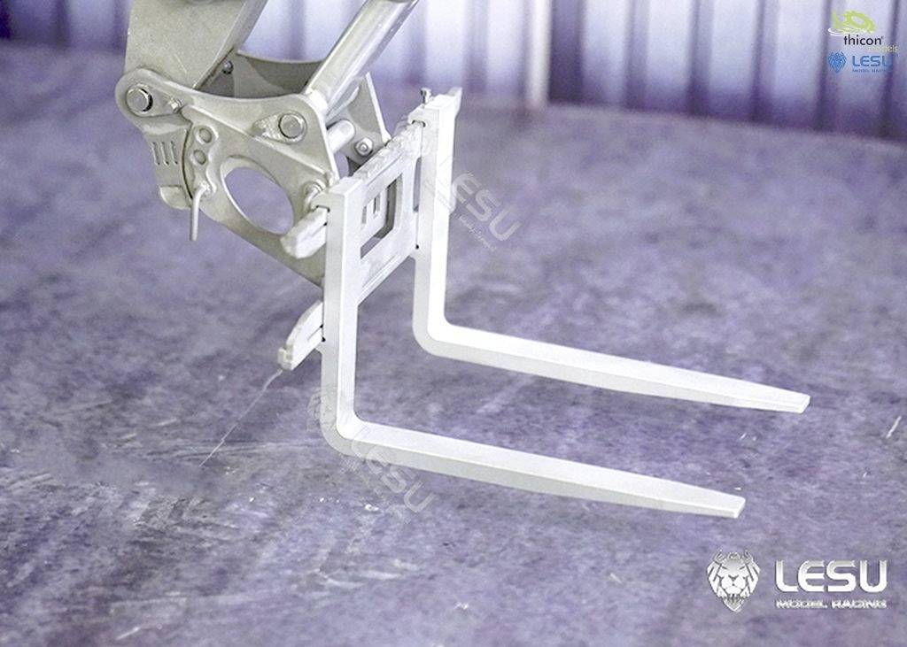 'Metalowy chwytnik na powierzchni podłoża, prawdopodobnie część urządzenia przemysłowego lub pojazdu. W tle widoczne logo LESU i thicon.'