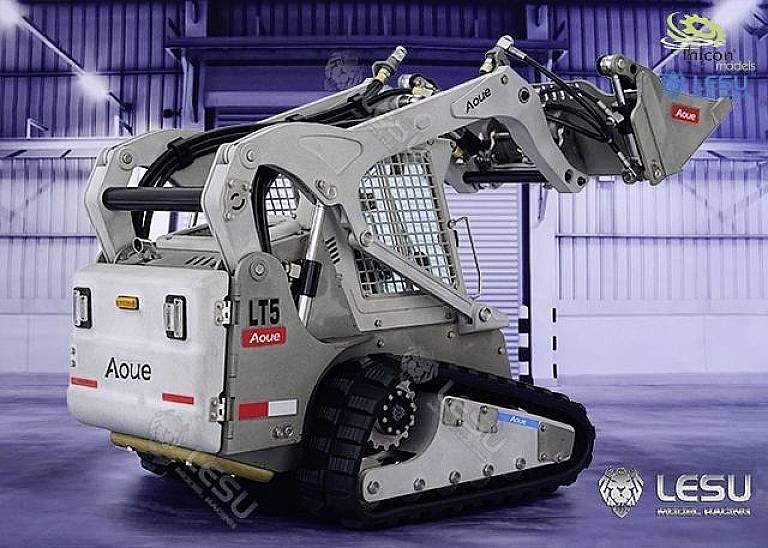 Kompaktowy, srebrny robot budowlany z gąsienicowym podwoziem i hydraulicznym ramieniem, sfotografowany w przemysłowym środowisku magazynowym.