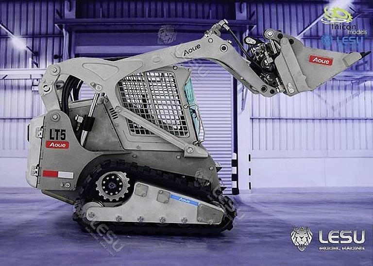 Kompaktowy, srebrny koparka w profilu w hali warsztatowej. Ruchowe ramię skierowane do przodu z chwytakiem. Logo marki 'Lesu'.