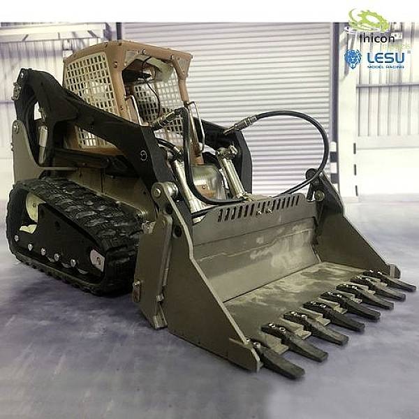 Mały model ładowarki gąsienicowej z zamontowaną łyżką stoi w warsztacie.