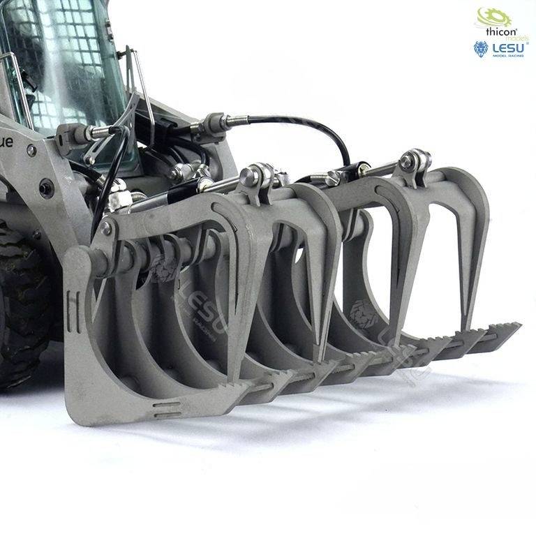 Szara ładowarka kołowa z osprzętem chwytakowym na białym tle, z logotypami marek widocznymi w górnym prawym rogu.