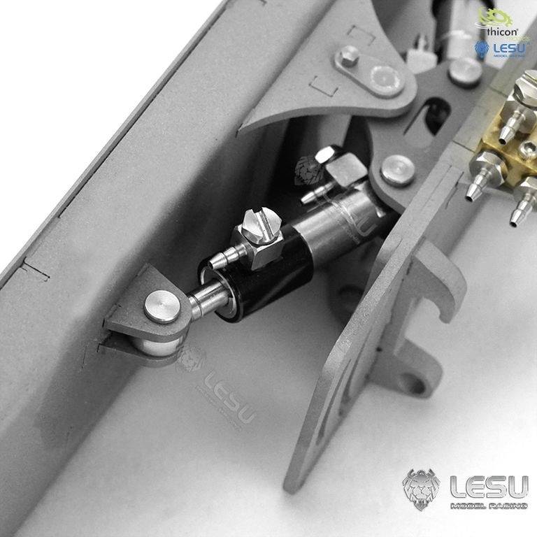 Zbliżenie metalowego mechanizmu z kołami zębatymi i śrubami, prawdopodobnie będącego częścią modelu lub elementem maszyny.