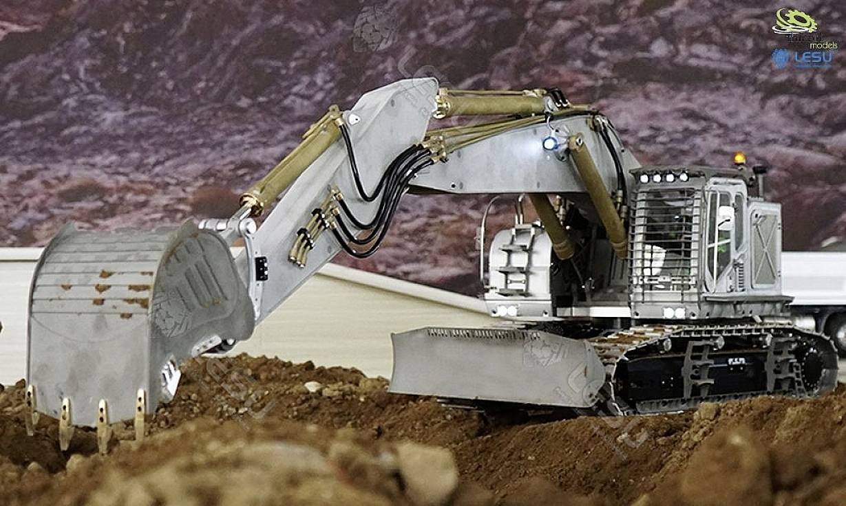 Srebrzysto-szary koparka podnosi ziemię swoją łyżką. Znajduje się na placu budowy z ziemistym podłożem w tle.