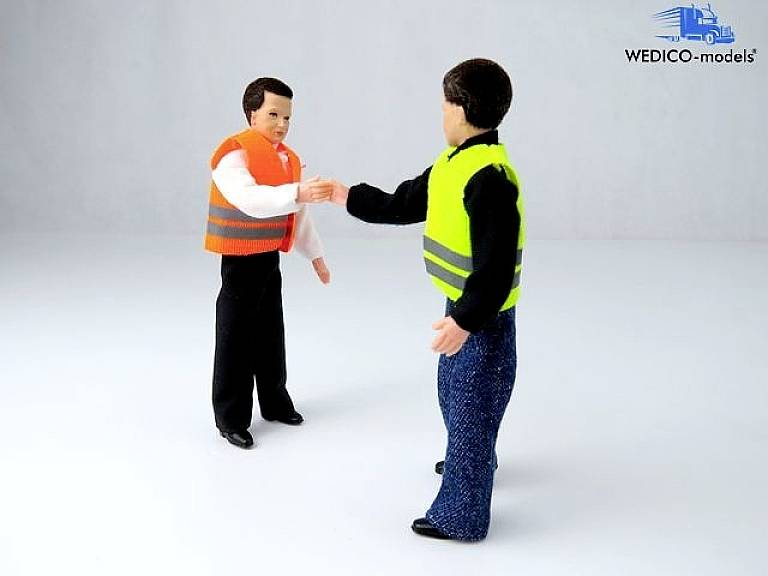Dwie miniaturowe figurki podają sobie ręce, ubrane w kamizelki ostrzegawcze. Po lewej stronie pomarańczowa, po prawej żółta z elementami odblaskowymi. Logo w prawym górnym rogu 'WEDICO-models'.