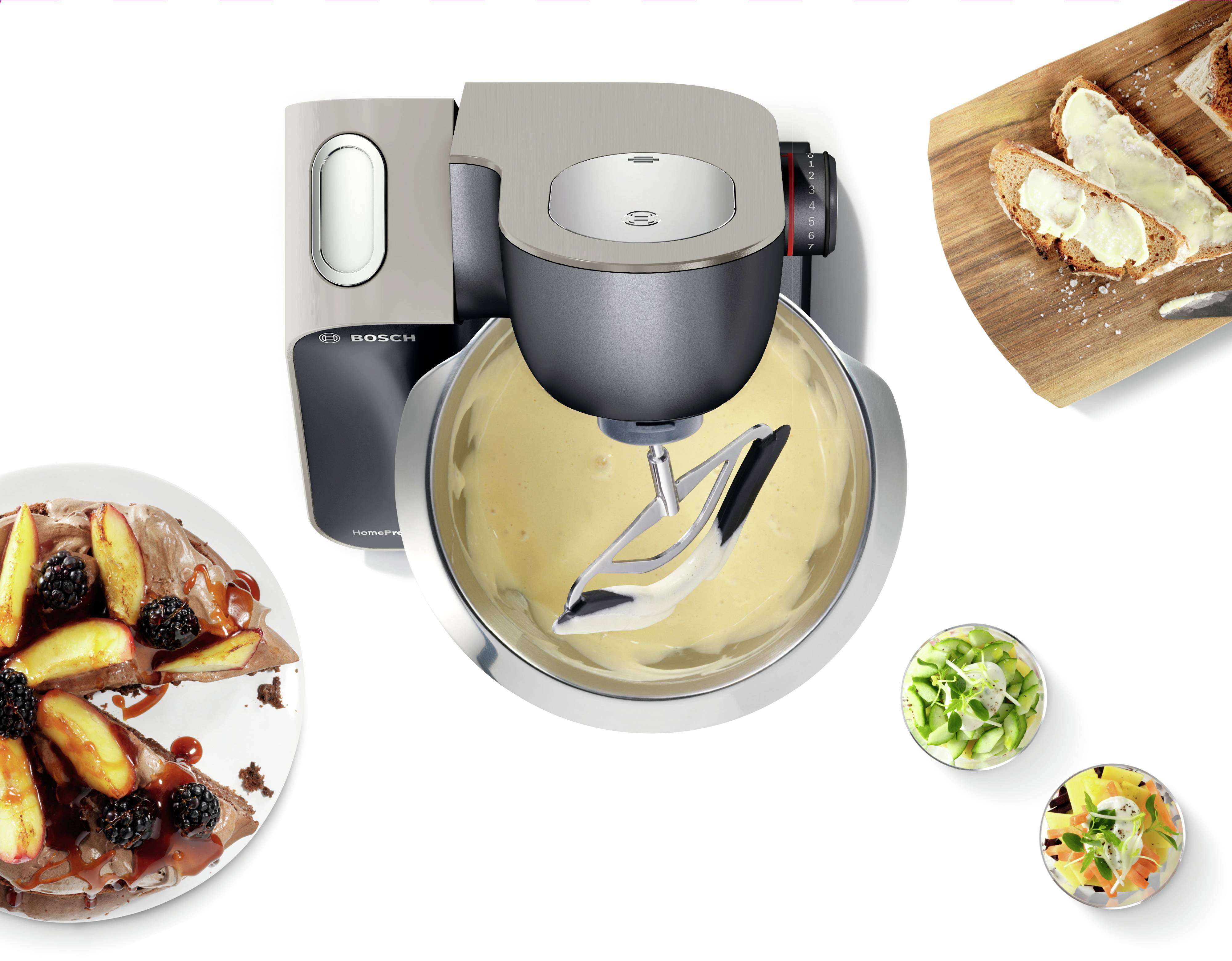 'Widok z góry na robot kuchenny z miską do mieszania, otoczony ciastem jabłkowym, kromkami chleba z masłem i składnikami w małych miseczkach.'