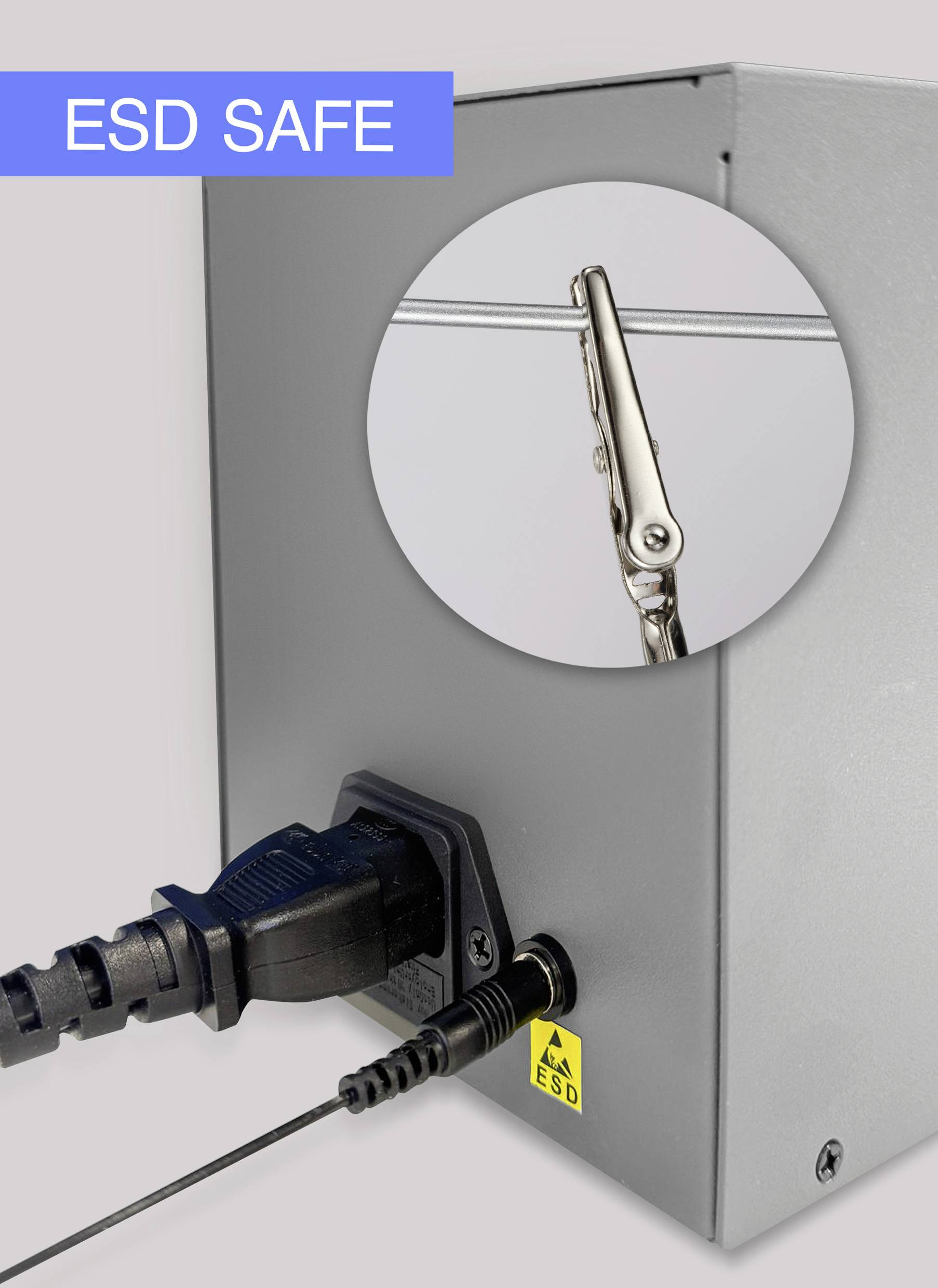 Srebrne urządzenie z podłączeniami kablowymi. Okrągłe okno wyróżnia zacisk krokodylkowy. W lewym górnym rogu widnieje napis 'ESD SAFE'.