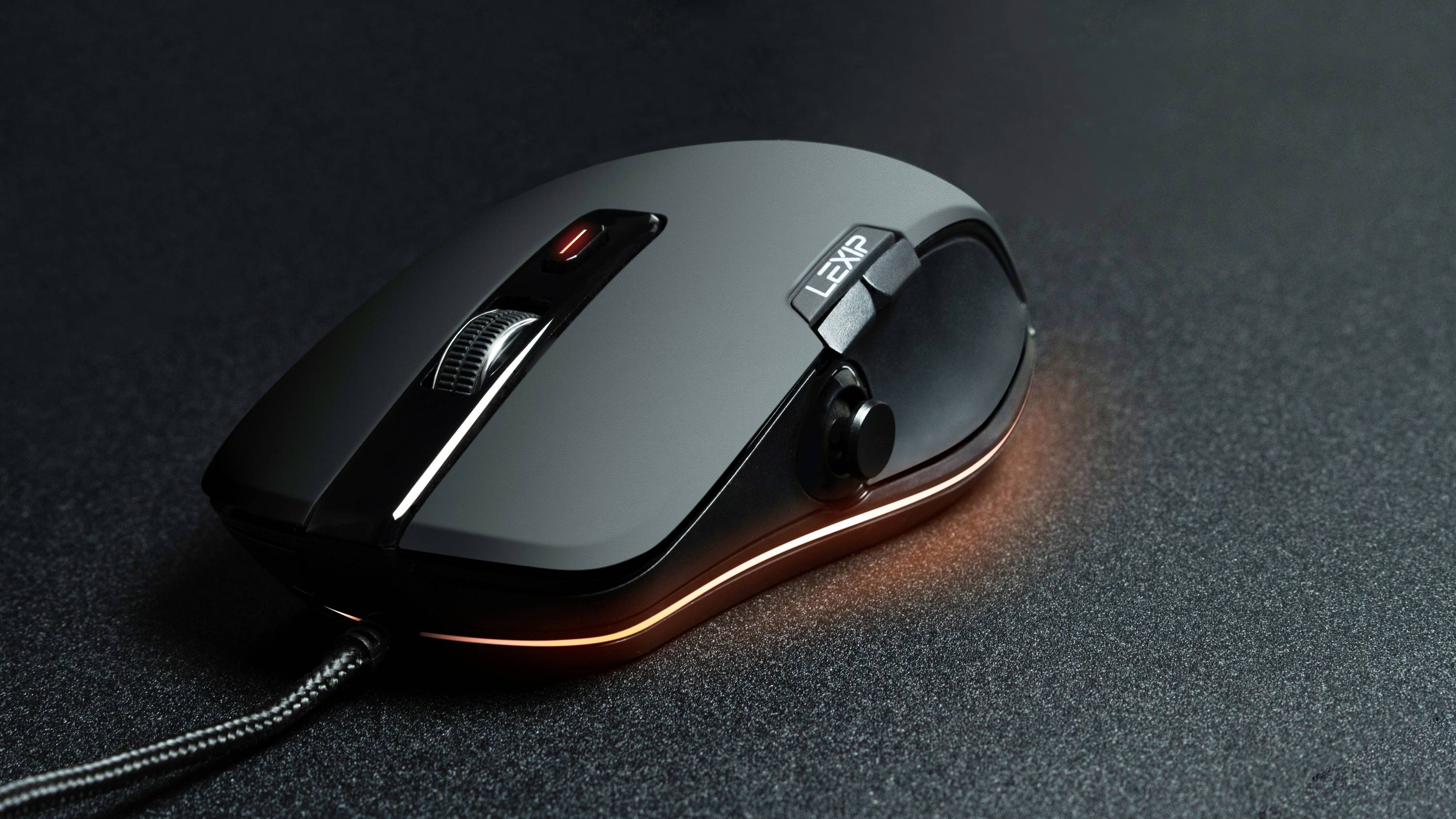 Czarna myszka komputerowa z podświetleniem LED od spodu, umieszczona na ciemnej powierzchni.