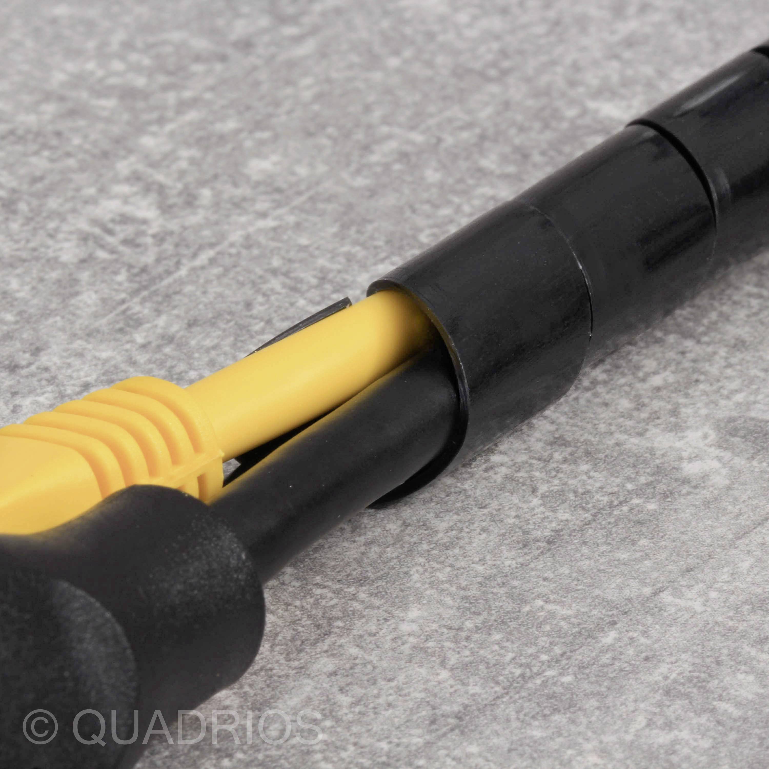 Zbliżenie żółtego kabla sieciowego w czarnym adapterze na szarym tle.