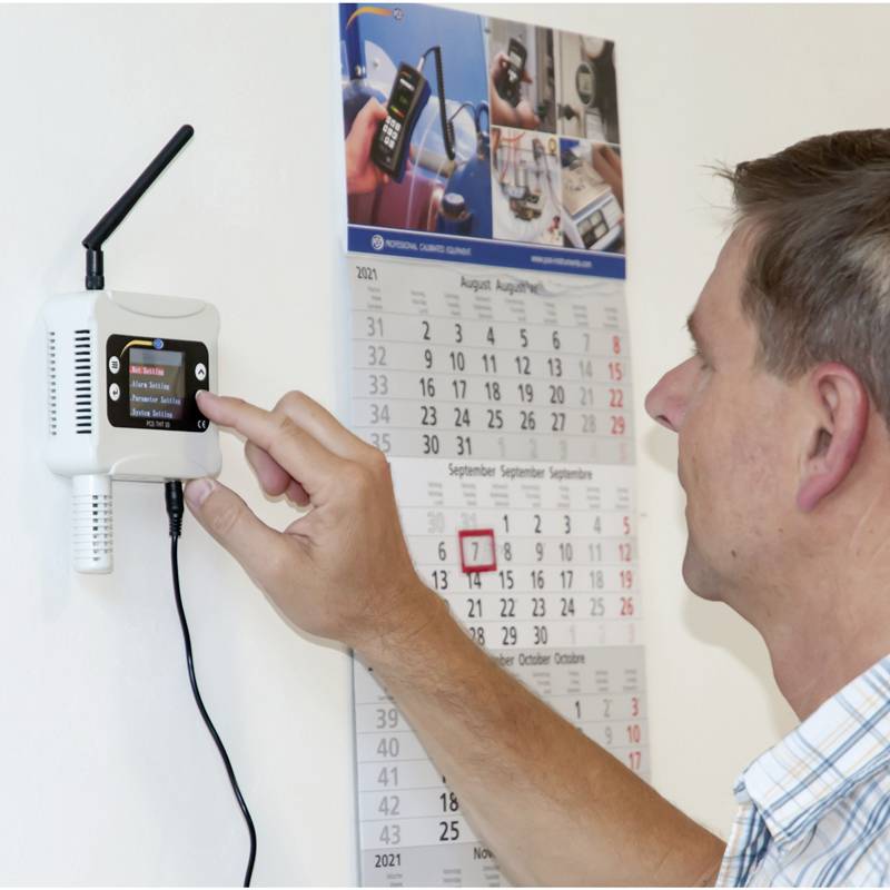 Mężczyzna ustawia system nadzoru UHF na ścianie, podczas gdy w tle wisi kalendarz.