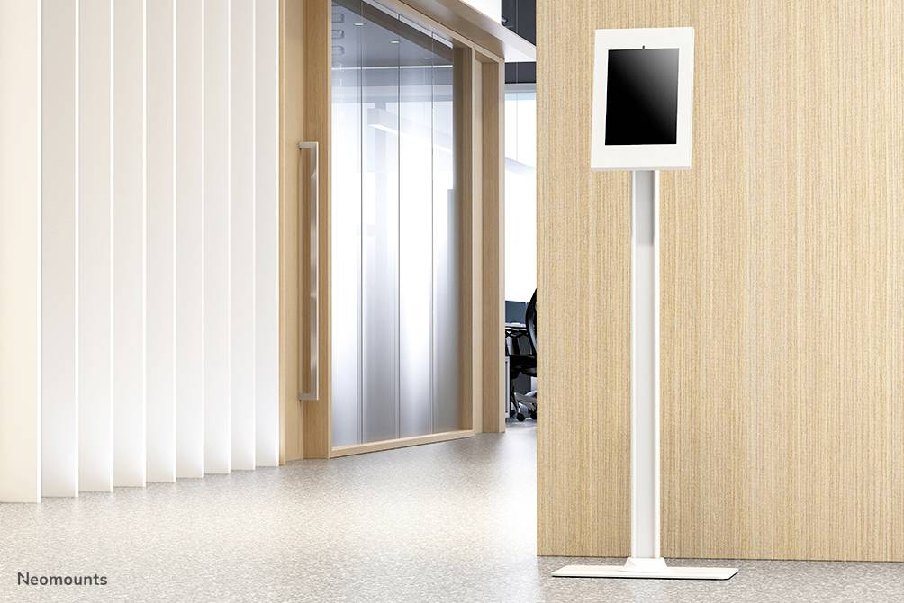 Tablet na wysokim, białym stojaku przed ścianą z drewna i szkła w nowoczesnym biurze.