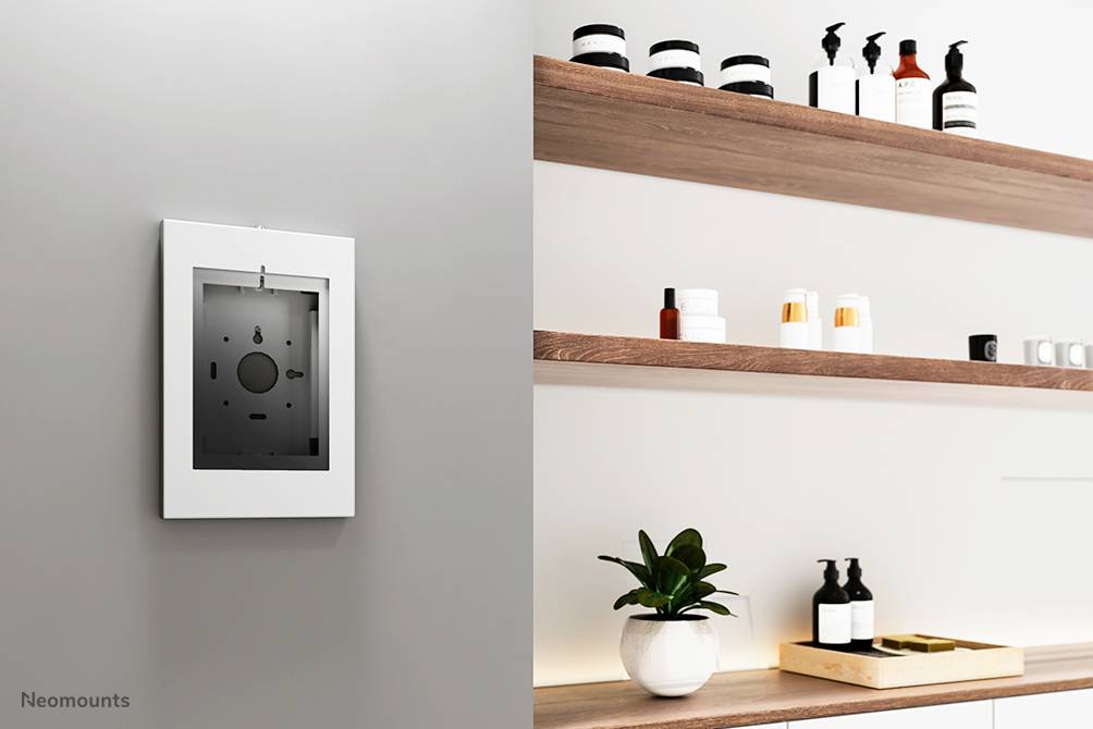 Minimalistyczny układ łazienki z zamontowanym na ścianie lustrem po lewej stronie oraz drewnianymi półkami po prawej, na których znajdują się kosmetyki i roślina.