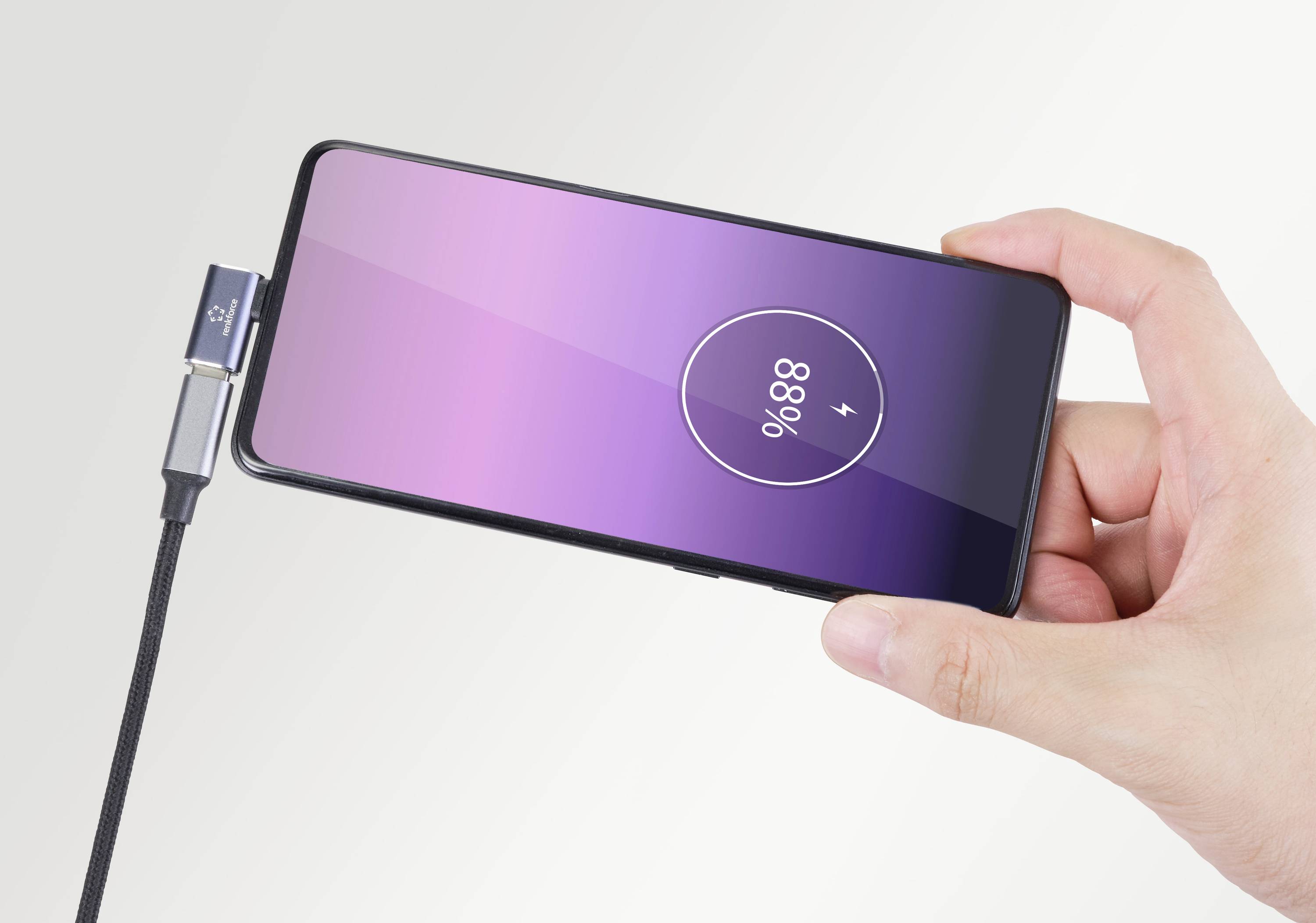 Smartfon trzymany w ręce z ekranem ładowania, wyświetlającym 88% poziomu baterii. Ładowarka podłączona, tło w miękkich odcieniach różu i fioletu.